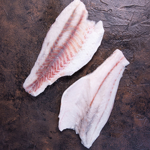 Frozen skinless boneless barramundi fillets on dark stone